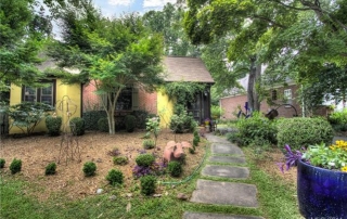 Home with brown brick and yellow stucco stone walkway flowers and bushes planted in front yard