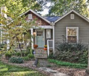 Gray siding home with white trim brown shingle details blue front door front porch with two white rocking chairs