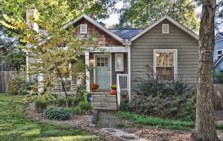 Gray siding home with white trim brown shingle details blue front door front porch with two white rocking chairs