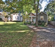 Gray siding home with white trim brown shingle details blue front door front porch with two white rocking chairs