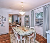 Dining room with white walls white molding wood floors blue curtains in front of window open to living room