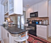 Kitchen with white cabinets black countertops black oven black microwave tile flooring white walls