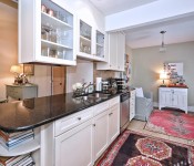 Kitchen with white cabinets black countertops black fridge tile flooring light brown walls open to dining room and living room