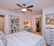 Bedroom with white walls dark wood ceiling fan white molding carpet flooring white furniture