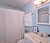 Bathroom with blue walls white cabinets white countertop white toilet medicine cabinet