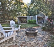 Backyard with green grass and trees hammock and fire pit open shed with eating area