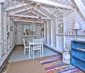 Open shed with cement floors white wood walls dining area with table and chairs