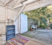 Open shed with cement floors white wood walls open to patio with white bench