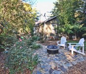 Backyard with green grass and trees hammock and fire pit with stone paved ground