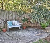 Backyard with cement patio with white bench and fenced in yard