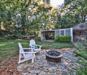 Backyard with green grass and trees hammock and fire pit open shed with eating area