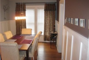 Dining room with wood floors brown walls brown curtains in front of windows white chair molding halfway up walls