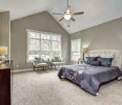 Master bedroom with high pitched ceiling gray walls ceiling fan white trim windows white baseboards carpet flooring