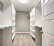 Walk in closet with gray walls white baseboards carpet flooring white built in shelves and rods white door