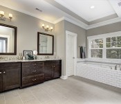 Bathroom with gray tile floors gray walls gray trim double windows white doors white baseboards recessed lighting tray ceiling white subway tile soaking tube and walk in shower