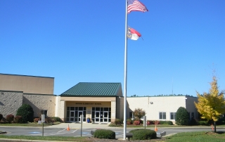 Marvin Elementary School brick building with green roof American flag and North Carolina flag waving on flag pole bright blue sky