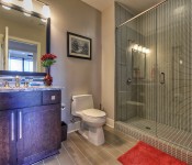 Bathroom with gray tile floors gray walls brown cabinet gray countertop gray tile shower glass shower door