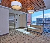 Sitting area pattern carpet white walls elevator wood ceiling floor to ceiling window with view of uptown Charlotte skyline