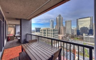 Porch with metal railing wood furniture wood floor orange rug view of uptown Charlotte skyline