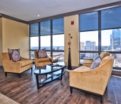 Sitting area with yellow walls wood floors large floor to ceiling windows view of uptown Charlotte yellow furniture