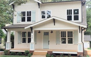 White shingle and siding two story home mint colored shutters and front door black gutters and details front porch with light wood floors
