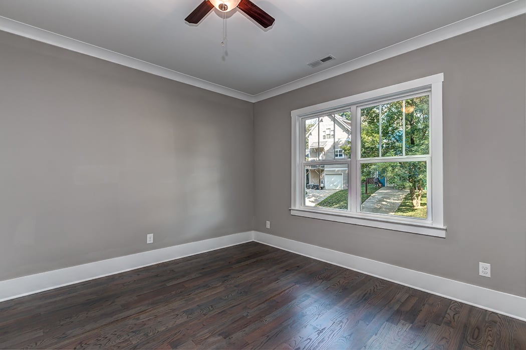 Empty room with gray walls wood ceiling fan wood floors white baseboards and white trim windows
