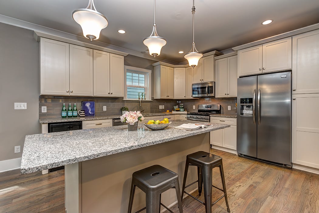 Kitchen with white cabinets gray granite countertops stainless steel appliances gray tile backsplash pendant lighting over island recessed lighting