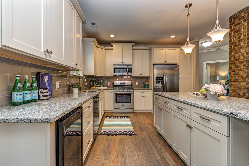 Kitchen with white cabinets gray granite countertops stainless steel appliances brick column pendant lighting over island recessed lighting