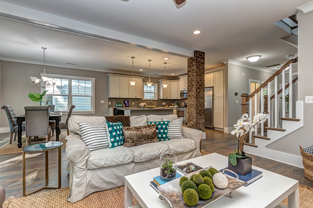 Living room open to dining room and kitchen wood floors brick beam in the middle white cabinets stainless steel appliances farmhouse decor