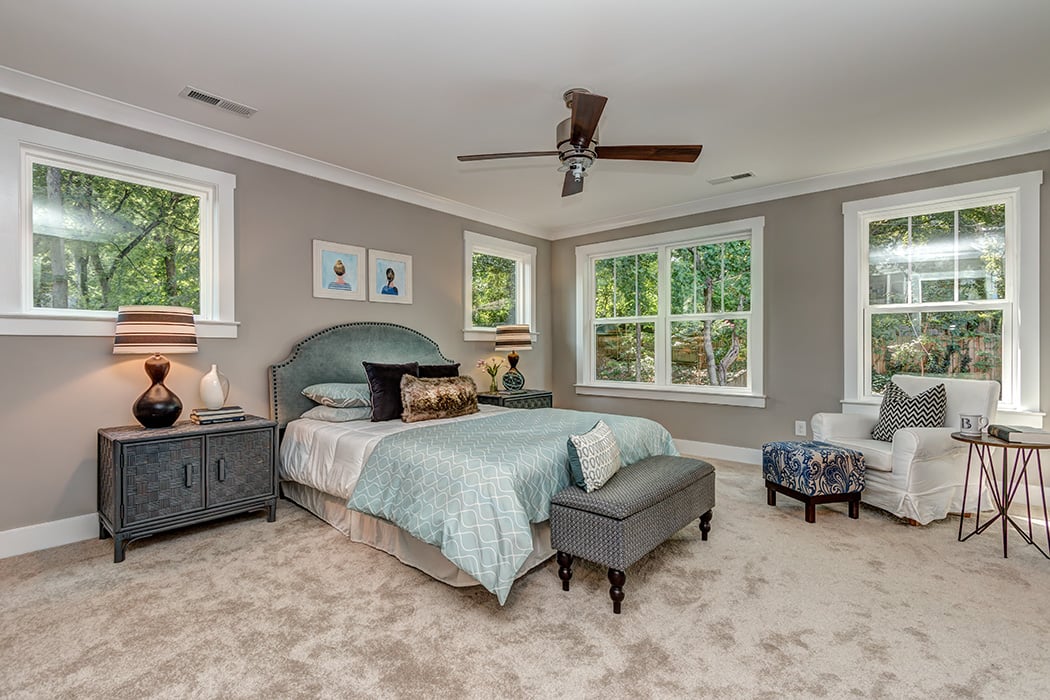 Bedroom with gray paint white baseboards and white trim windows brown ceiling fan and carpet