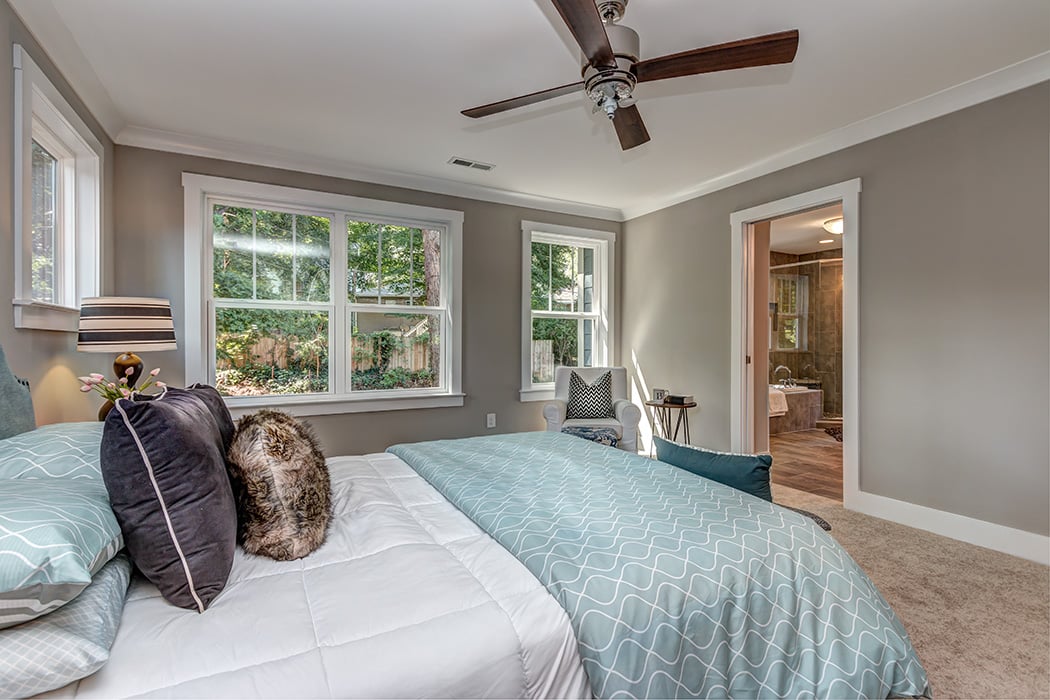 Bedroom with gray paint white baseboards and white trim windows brown ceiling fan and carpet