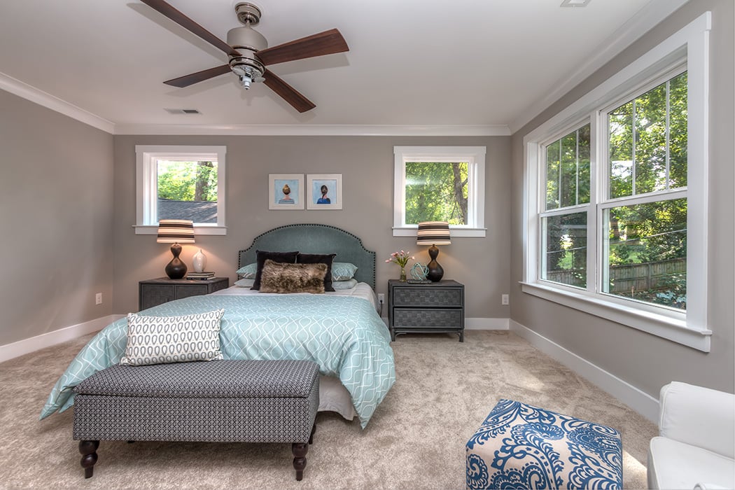 Bedroom with gray paint white baseboards and white trim windows brown ceiling fan and carpet