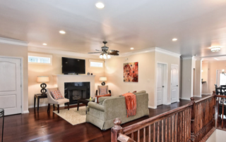 Living room with light walls white trim white doors built in fireplace recessed lighting wood ceiling fan wood floors wood banister