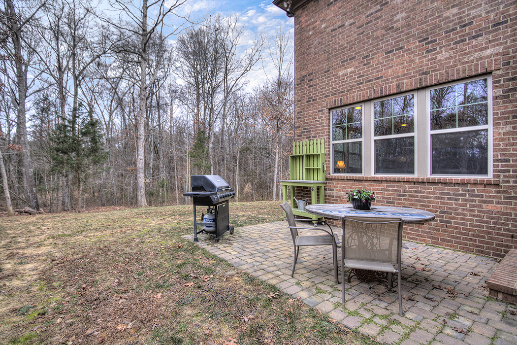 Back patio with brick floor grill and eating area trees in background