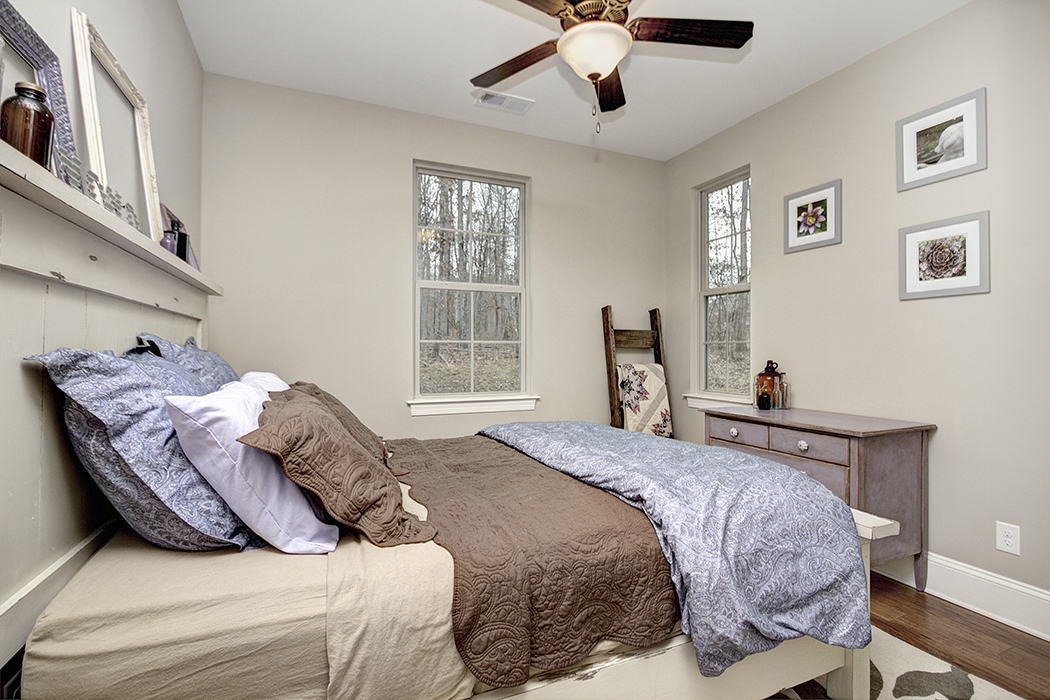 Bedroom with neutral walls wood floors white baseboards wood fan two windows