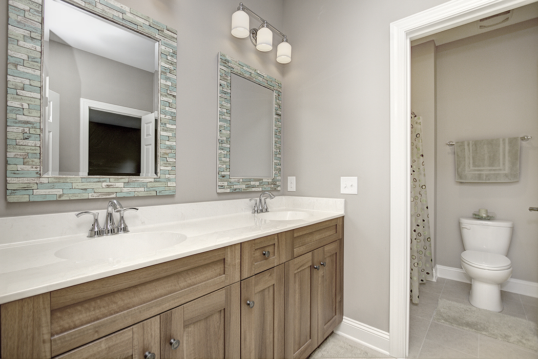 Bathroom with wood cabinets white countertops tile framed mirrors separate toilet area