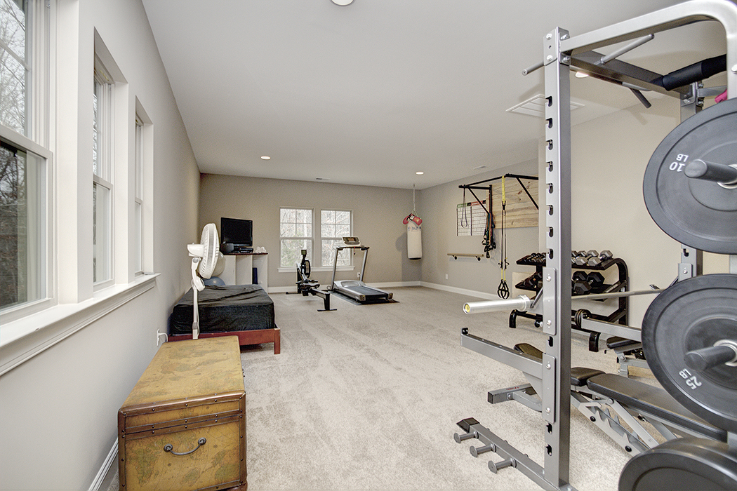 Home gym with gray walls carpet windows white baseboards treadmill weight stations rowing machine