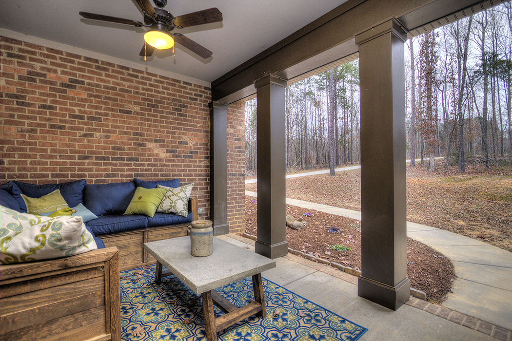Porch with brown brick walls brown columns brown ceiling fan cement floors blue brown and green furniture and decor