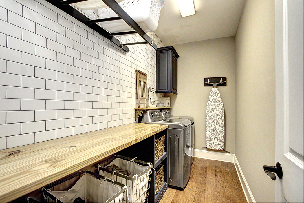 Laundry room with gray washer and dryer white subway tile wall with dark grout black cabinets