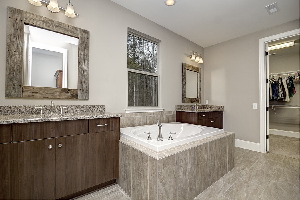 Bathroom with gray walls gray tile floor dark wood cabinet gray granite countertop gray tile covered bathtub