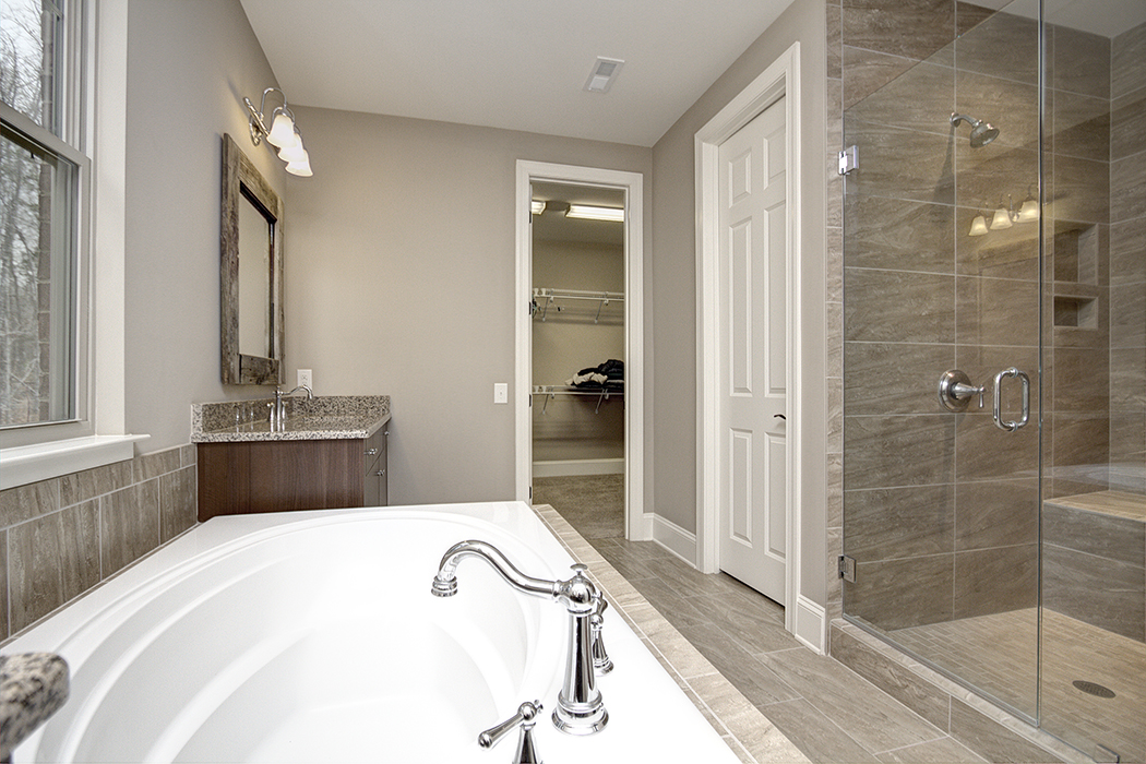 Bathroom with gray walls gray tile floor gray tile shower with glass door dark wood cabinet gray granite contertop