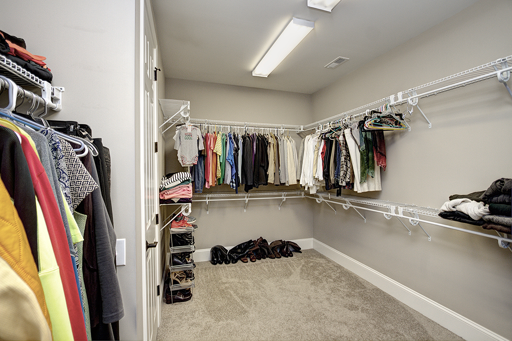 Large closet gray walls white baseboards carpet fluorescent lighting wire shelving