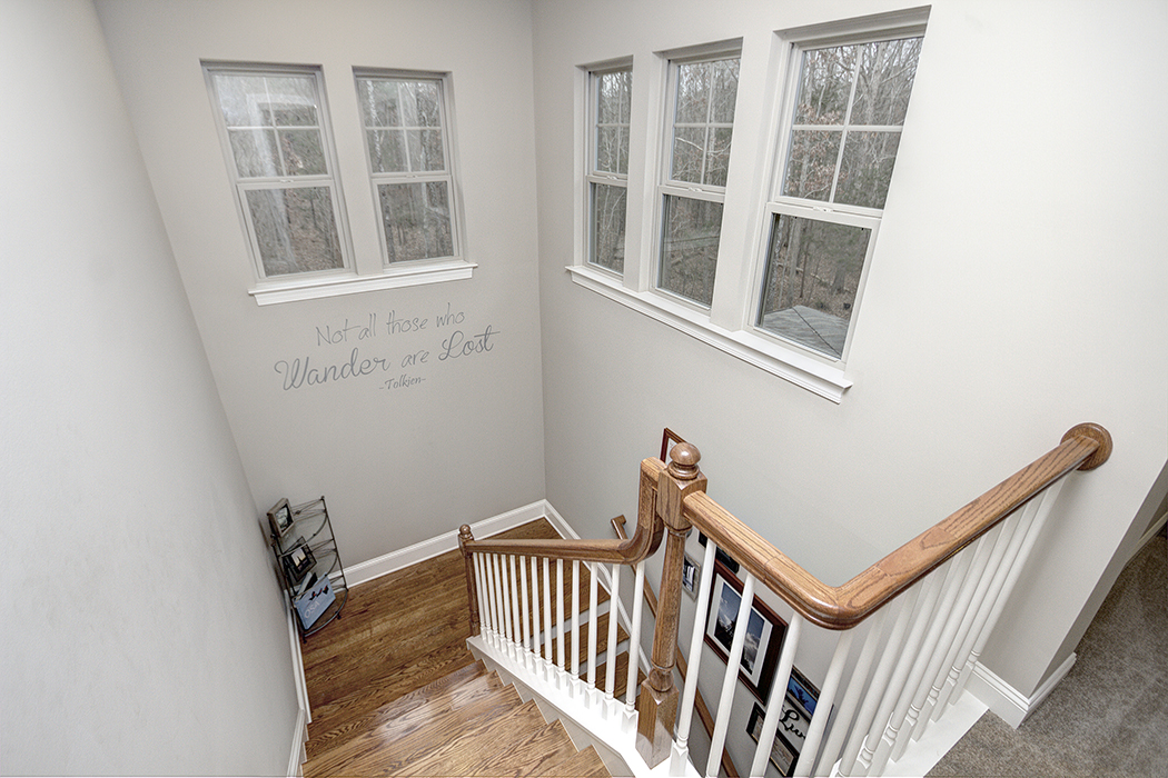 Staircase with windows on second floor wood stairs wood banister white railing white baseboards gray carpet second floor