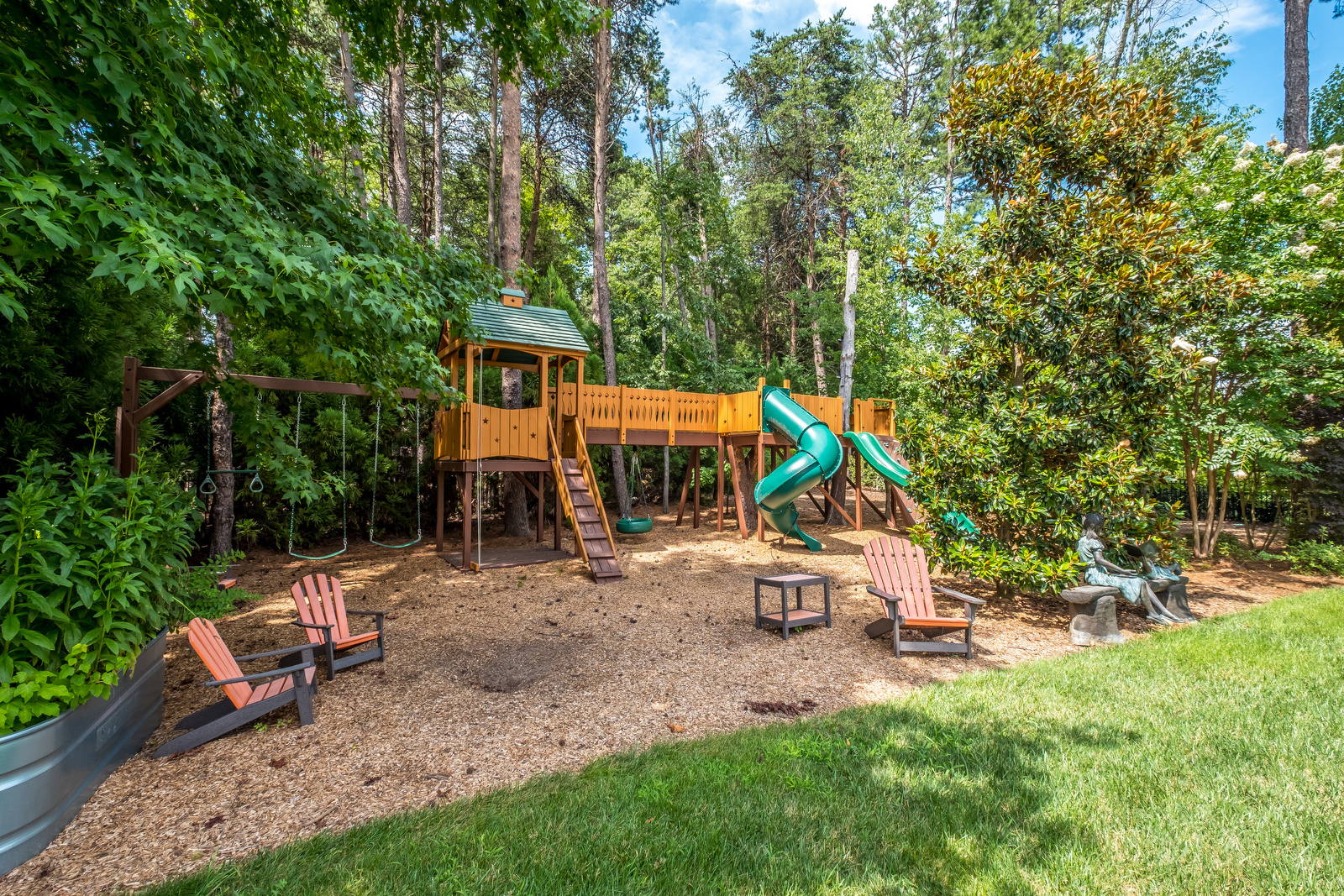 Backyard with playground brown wood with green slides green swings green details green grass and trees surrounding it