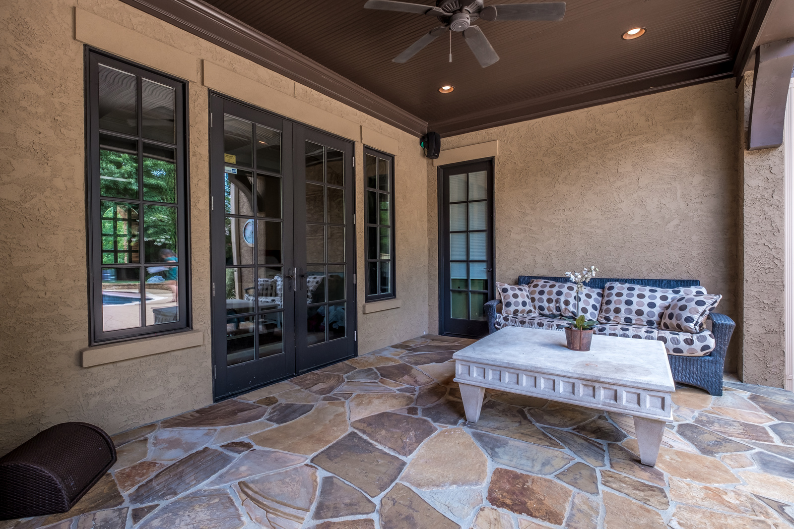 Back porch with tile floor brown stucco walls dark brown windows and doors brown ceiling and ceilg fan