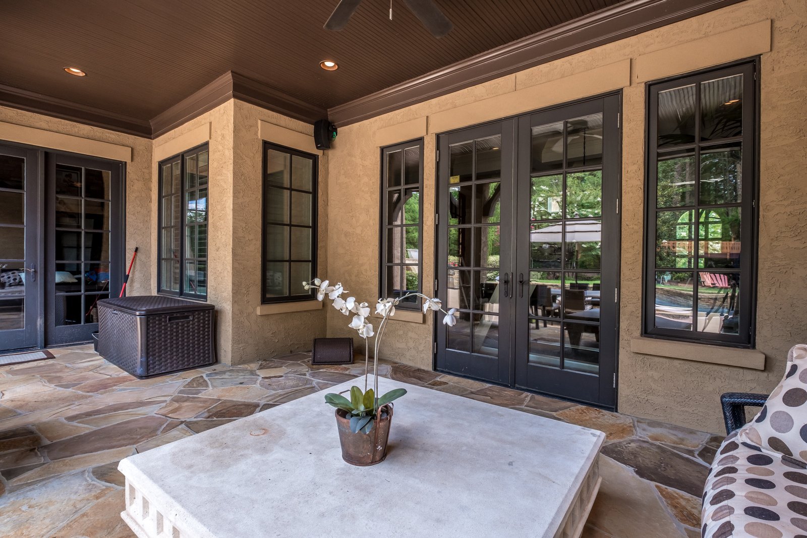 Back porch with tile floor brown stucco walls dark brown windows and doors