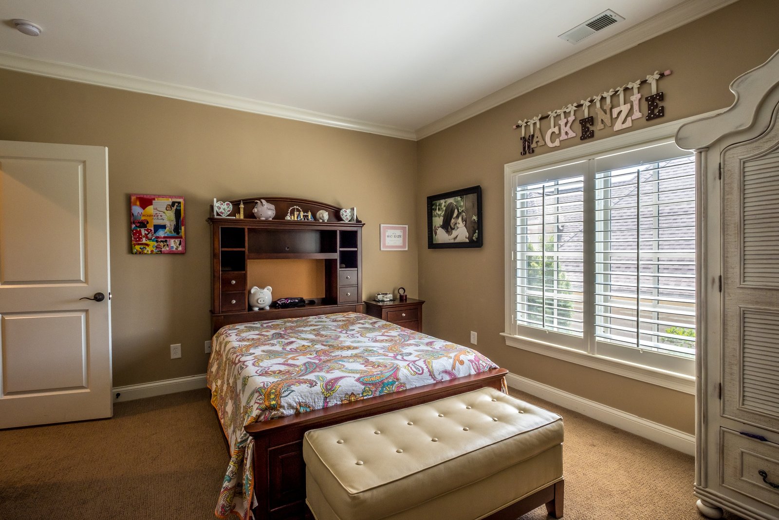 Bedroom with brown walls white trim light brown carpets dark wood furniture white bookshelf white armoire