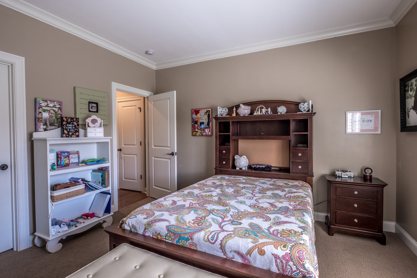 Bedroom with brown walls white trim light brown carpets dark wood furniture white bookshelf