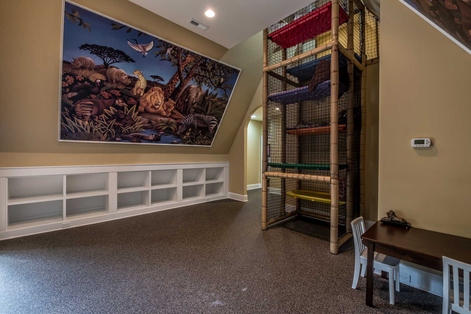 Playroom with mat floor light brown walls built in white cubbies huge animal mural on the wall large play climbing area