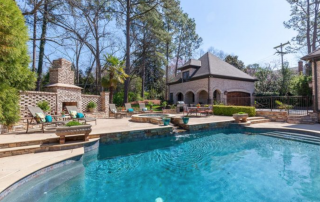 Backyard pool with built in hot tub and fireplace pool house in background